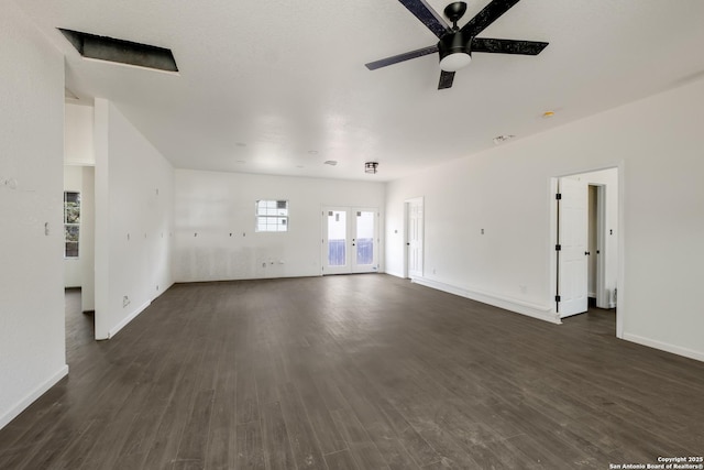 unfurnished living room with dark wood-style floors, a ceiling fan, and baseboards