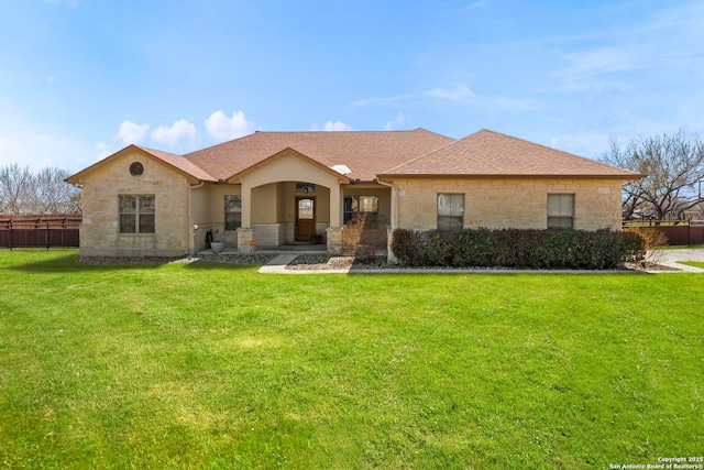 single story home featuring a front yard, fence, stone siding, and roof with shingles