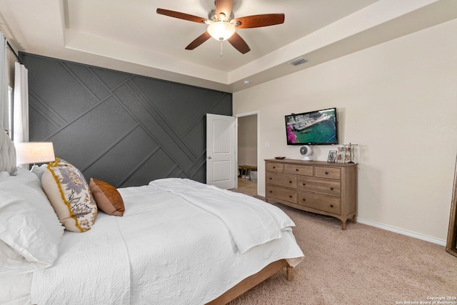 bedroom with visible vents, light carpet, a raised ceiling, baseboards, and ceiling fan