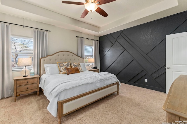 bedroom featuring light colored carpet, a tray ceiling, and multiple windows