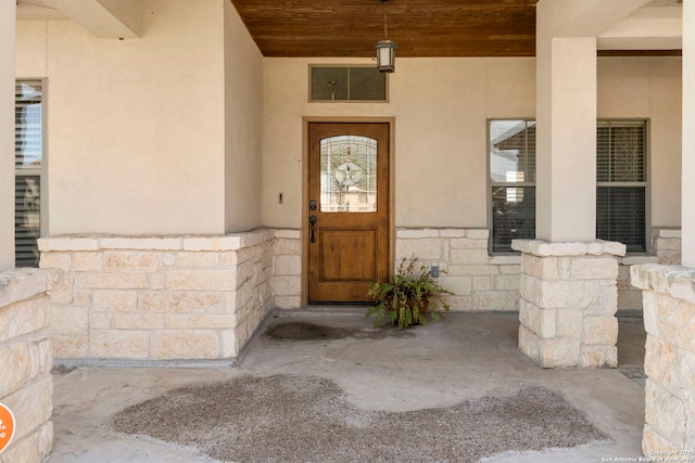 view of exterior entry featuring stucco siding and stone siding