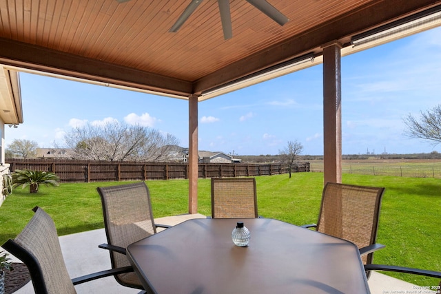 view of patio / terrace with a rural view, outdoor dining area, a fenced backyard, and a ceiling fan