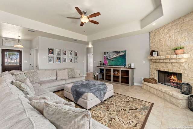 living area with tile patterned floors, a fireplace, visible vents, and a tray ceiling