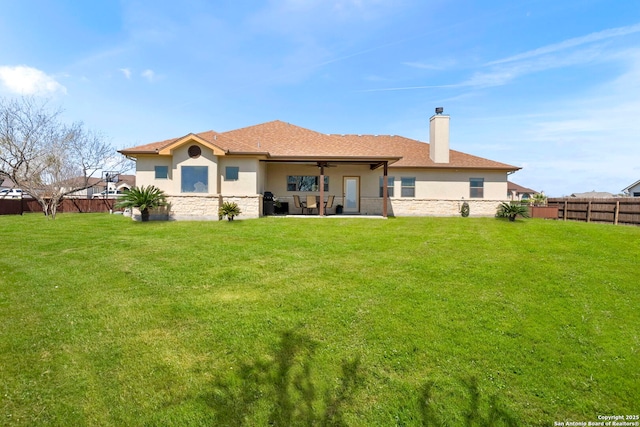 rear view of property featuring a patio, a ceiling fan, fence, a yard, and stucco siding