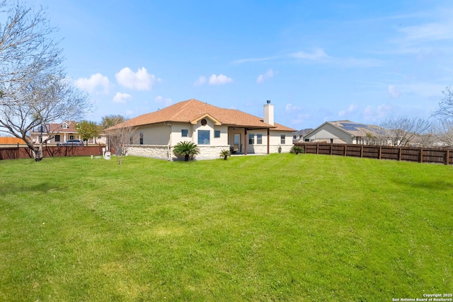 back of property featuring a yard, a fenced backyard, a chimney, and stucco siding