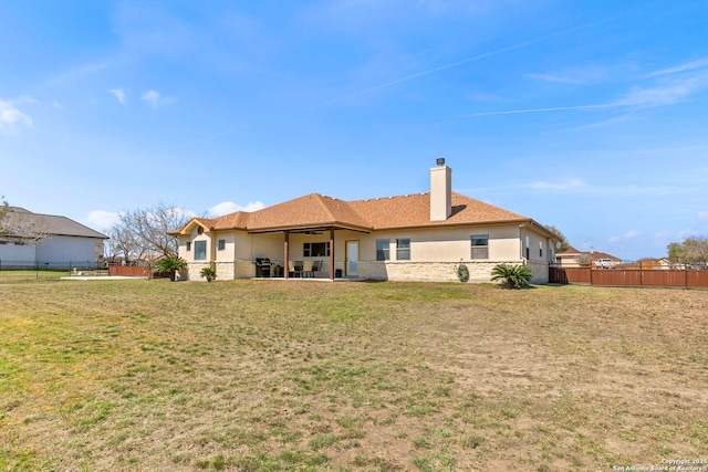 back of house with stucco siding, a lawn, a patio, and fence