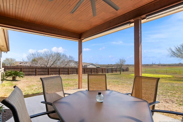 view of patio / terrace with outdoor dining area, a rural view, a fenced backyard, and a ceiling fan