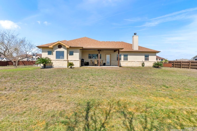 rear view of property featuring a patio, a ceiling fan, a yard, a fenced backyard, and stucco siding