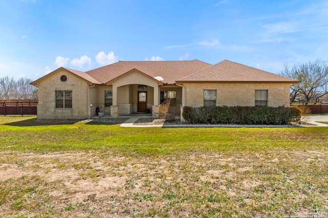 view of front facade featuring fence, roof with shingles, stucco siding, a front lawn, and stone siding