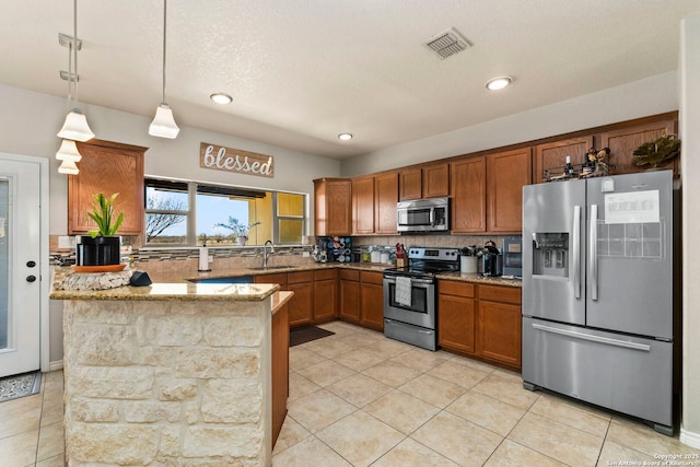 kitchen with visible vents, brown cabinets, a sink, appliances with stainless steel finishes, and a peninsula