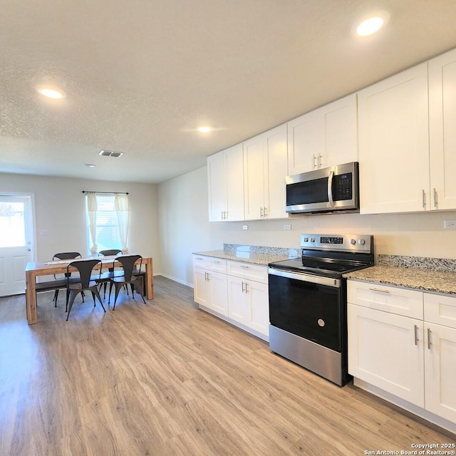 kitchen with visible vents, light wood finished floors, white cabinets, appliances with stainless steel finishes, and a textured ceiling