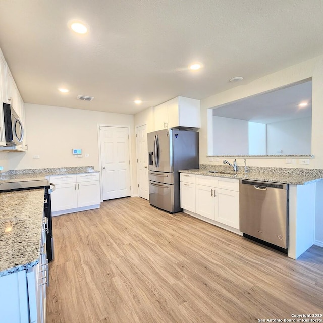 kitchen featuring a sink, stainless steel appliances, white cabinets, and light wood finished floors