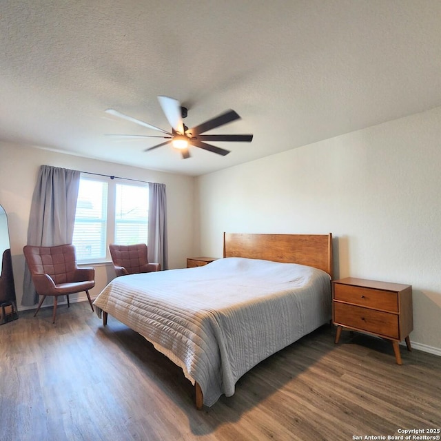 bedroom with ceiling fan, wood finished floors, baseboards, and a textured ceiling