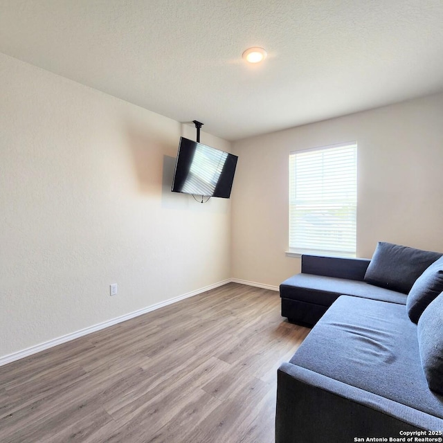 living room with wood finished floors, baseboards, and a textured ceiling