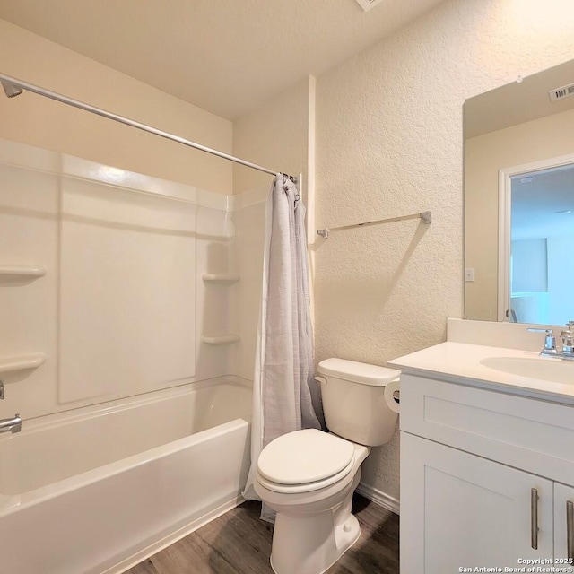 bathroom with toilet, shower / tub combo with curtain, wood finished floors, a textured wall, and vanity