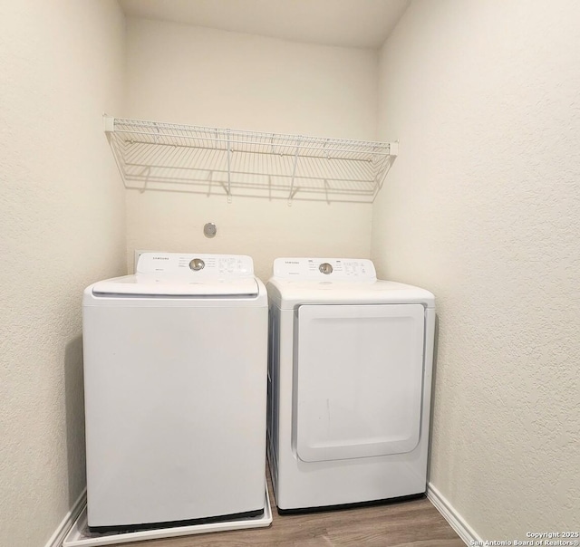 laundry area featuring laundry area, wood finished floors, washing machine and dryer, and baseboards