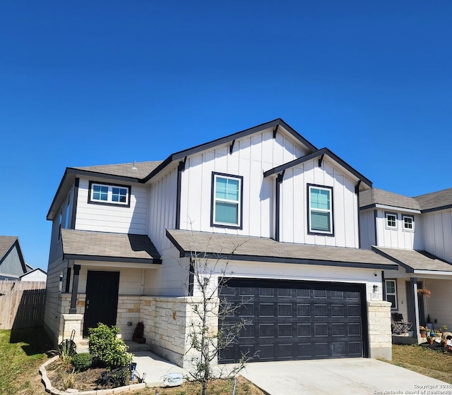 modern farmhouse style home with fence, driveway, an attached garage, stone siding, and board and batten siding