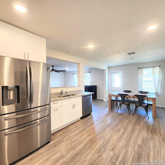 kitchen featuring a sink, stainless steel appliances, visible vents, and light wood finished floors