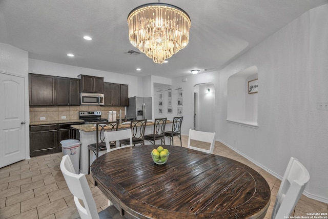 dining room featuring light tile patterned floors, visible vents, recessed lighting, arched walkways, and a notable chandelier