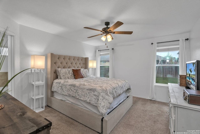 bedroom with a ceiling fan, multiple windows, and light colored carpet