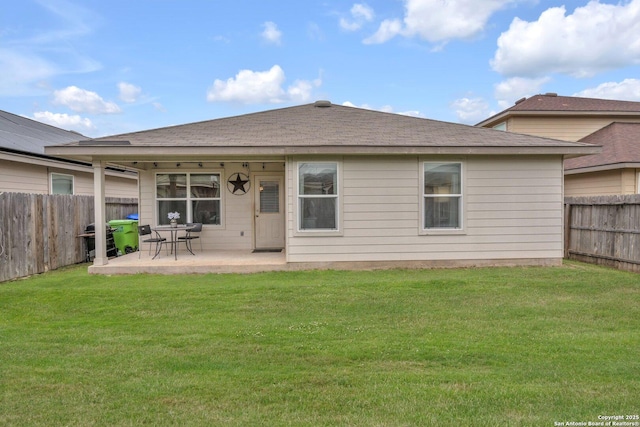 rear view of house featuring a lawn, roof with shingles, a fenced backyard, and a patio area