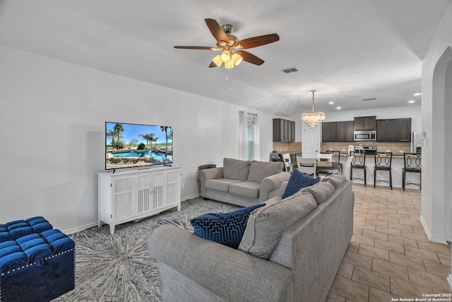 living room with baseboards, arched walkways, visible vents, and ceiling fan