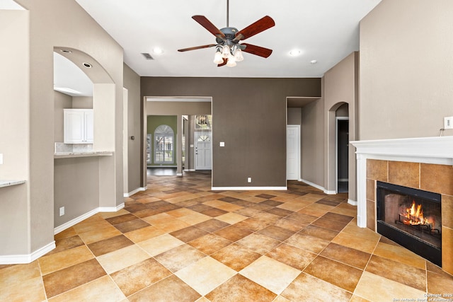 unfurnished living room featuring visible vents, baseboards, ceiling fan, and a tile fireplace