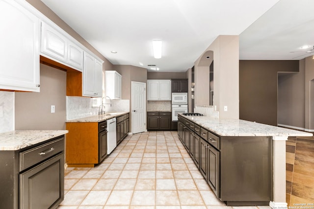 kitchen featuring backsplash, white appliances, white cabinetry, and light stone countertops