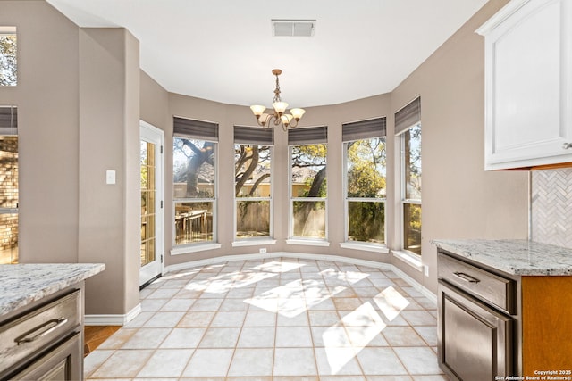 unfurnished dining area featuring a wealth of natural light, visible vents, baseboards, and an inviting chandelier