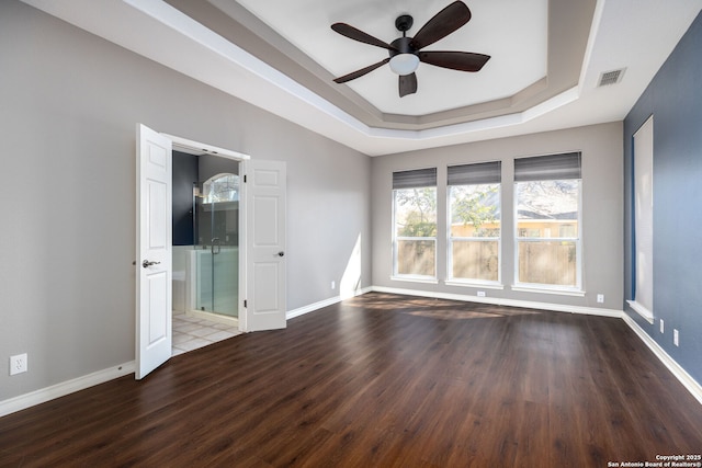 unfurnished room featuring a ceiling fan, wood finished floors, visible vents, baseboards, and a tray ceiling