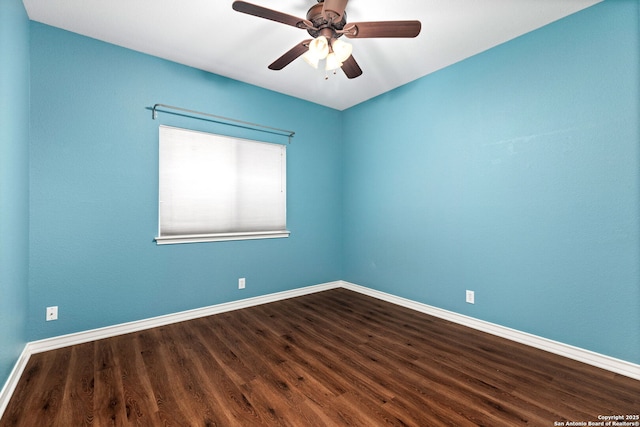 spare room with baseboards, dark wood-type flooring, and ceiling fan