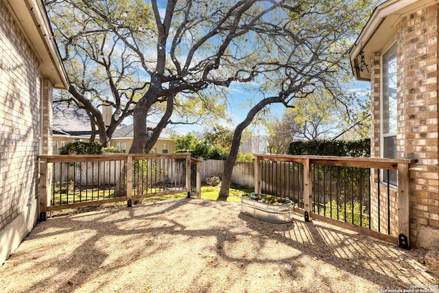 wooden terrace with a fenced backyard and a patio