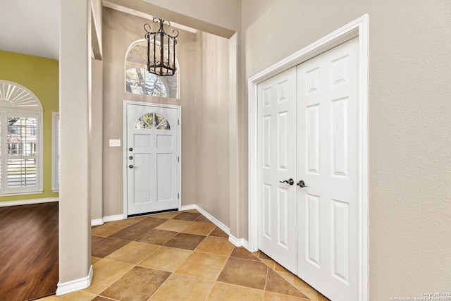 foyer with baseboards and a chandelier