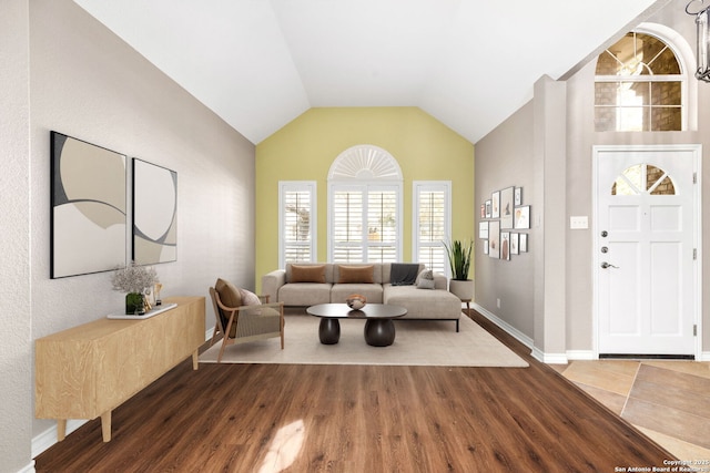 living room featuring lofted ceiling, wood finished floors, and baseboards