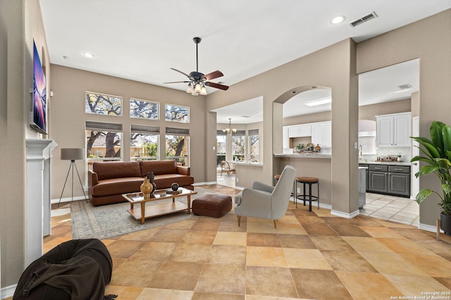 living room with baseboards, visible vents, recessed lighting, arched walkways, and ceiling fan with notable chandelier