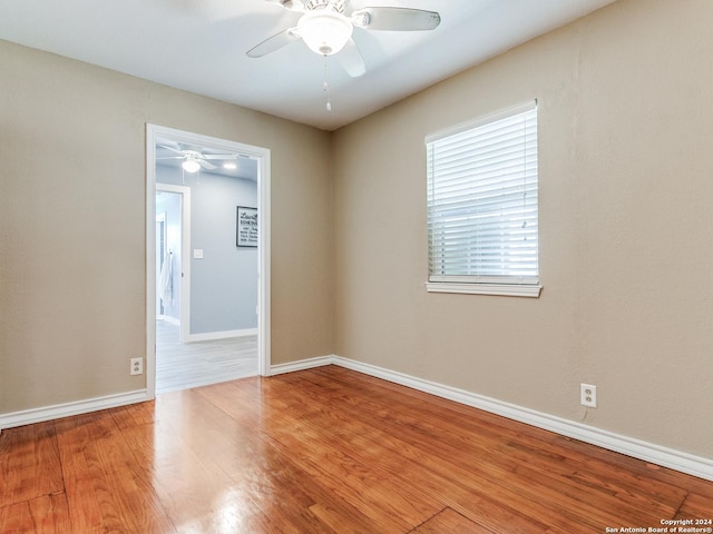 spare room featuring baseboards, wood finished floors, and a ceiling fan