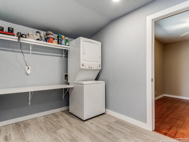 clothes washing area with light wood-type flooring, stacked washer and clothes dryer, and laundry area