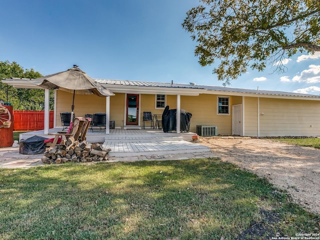 rear view of house with a yard, central AC, metal roof, and fence