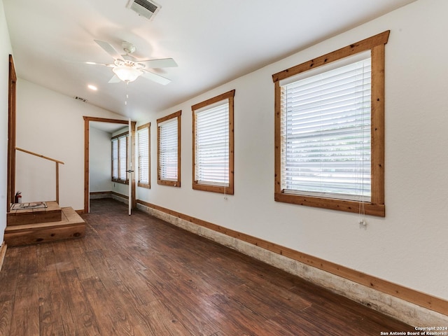 spare room featuring visible vents, a ceiling fan, baseboards, lofted ceiling, and dark wood-style flooring