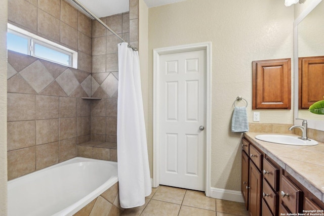 bathroom featuring tile patterned flooring, baseboards, vanity, and tiled shower / bath