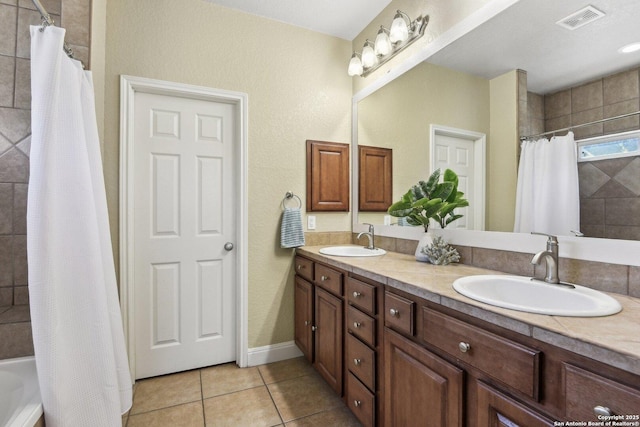 full bathroom featuring a sink, visible vents, double vanity, and tile patterned floors