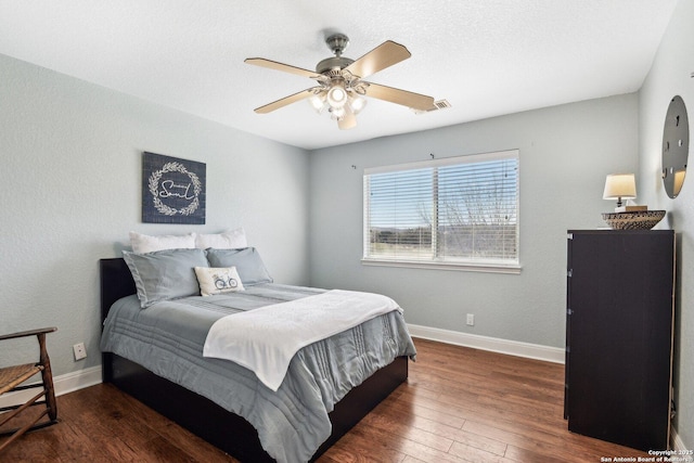 bedroom with hardwood / wood-style floors, baseboards, visible vents, and a ceiling fan