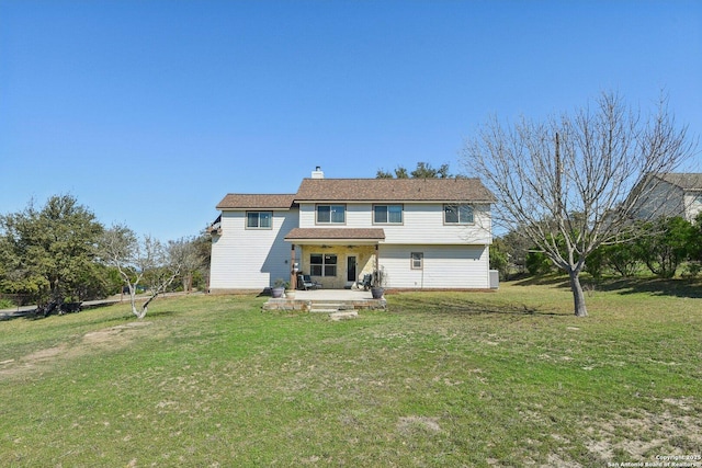 rear view of house with a yard, a chimney, and a patio area