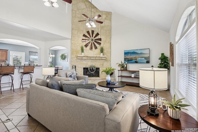 living room featuring arched walkways, plenty of natural light, a fireplace, and light tile patterned flooring