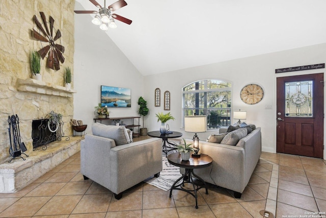 living room with light tile patterned floors, a stone fireplace, high vaulted ceiling, and ceiling fan