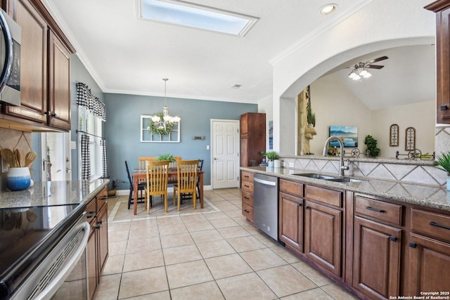 kitchen with ceiling fan with notable chandelier, a sink, light stone counters, stainless steel appliances, and light tile patterned flooring