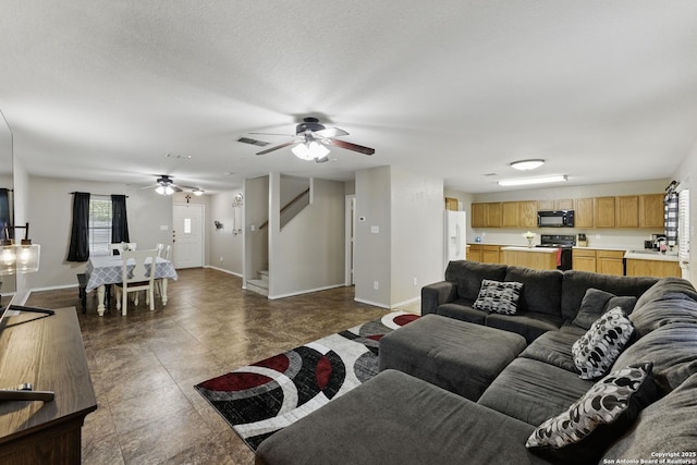 living area with visible vents, baseboards, ceiling fan, and stairs