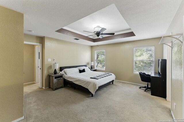 carpeted bedroom with visible vents, baseboards, a textured ceiling, a raised ceiling, and a ceiling fan