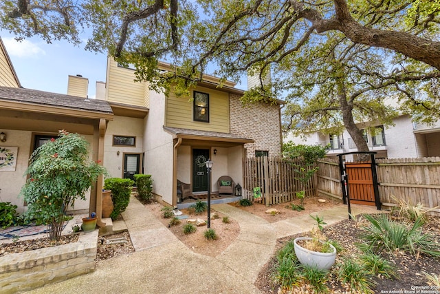 back of property with stucco siding, roof with shingles, and fence