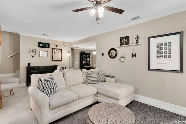 living room featuring visible vents, baseboards, crown molding, and stairway